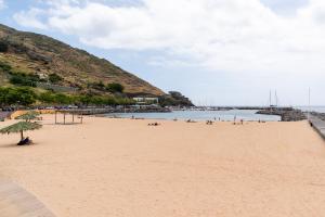 a beach with a bunch of people on it at Green Doors - AC and free parking in Machico