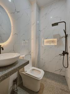 a white bathroom with a sink and a toilet at Rumahku Homestay in Makassar