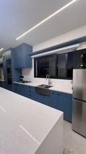 una cucina con armadi blu e frigorifero in acciaio inossidabile di Natureza, Paz e Conforto a Águas de Santa Barbara