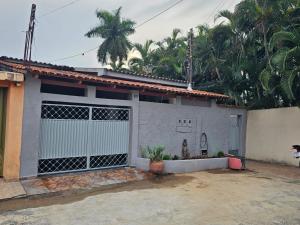 a white house with a gate and palm trees at CIG Hostel in Goiânia