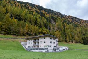 ein großes weißes Gebäude auf einem Feld vor einem Berg in der Unterkunft International House Sölden Studio ZW 3 in Sölden