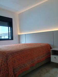 a bedroom with a bed with a red bedspread and a window at Refúgio em Palmas in Governador Celso Ramos