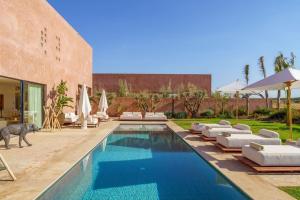 a pool with chairs and umbrellas next to a building at Dar Al Jenna - Villa de luxe avec piscine privée in Marrakech