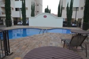 a swimming pool with a table and chairs next to a building at Olímpia Super Stay in Olímpia