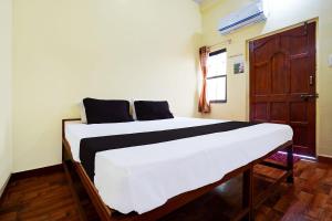 a bed in a room with a wooden door at Hotel O Madhur Inn in Rāipur