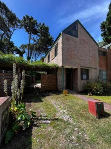 una casa di mattoni con un cortile con un muro di mattoni di Duplex Mardifiore Pinamar a Pinamar