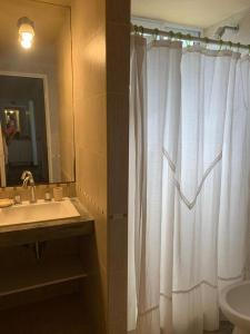 bagno con lavandino e tenda da doccia bianca di Duplex Mardifiore Pinamar a Pinamar