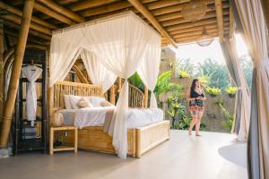 a woman standing in front of a bed in a room at Danaswari Bali Bamboo House in Selat
