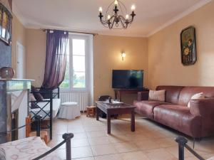a living room with a leather couch and a tv at Maison de caractère avec piscine chauffée, étang privé et proche forêt, à 90 min de Paris - FR-1-581-48 in La Chapelle-Fortin