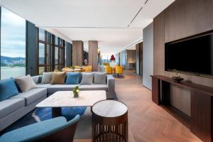 a living room with a couch and a flat screen tv at Grand Mercure Hangzhou Qingshan Lake in Hangzhou