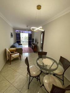 Apartamento na Quadra da Praia! في فيلا فيلها: غرفة معيشة مع طاولة وكراسي زجاجية