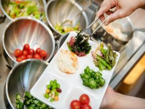 a person holding a plate with vegetables on it at APA Hotel Hakata Higashihieekimae in Fukuoka