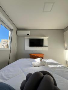 a bedroom with a bed with a tv on the wall at Apartamento Central 2 Quartos c Garagem in Pelotas +26 photos