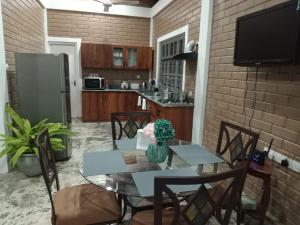 a kitchen with a table and chairs and a television at Villa Shendel in Gampaha