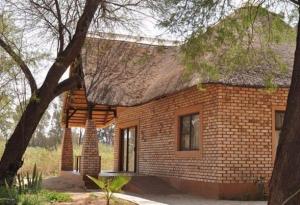 ein kleines Backsteinhaus mit einem Strohdach in der Unterkunft Kashana Namibia in Omaruru