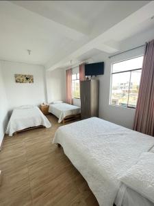 a bedroom with two beds and a window at Hotel Isla Vela Paracas in Paracas