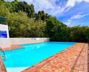 a large blue swimming pool with a brick floor and trees at Studio confort près des plages in Le Gosier