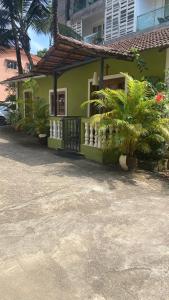 a green house with palm trees in front of it at Peter’s vacation rentals Goa in Calangute