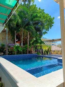 ein Swimmingpool in einem Resort mit Palmen in der Unterkunft La Casa Teresa Tourist Inn in El Nido
