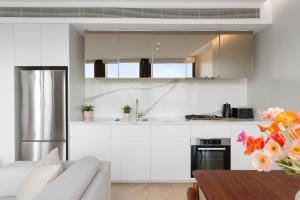a kitchen with white cabinets and a stainless steel refrigerator at Harbour Views, Fireworks & Secure Parking in Sydney