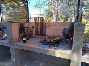 a fire pit with a grill and a bottle of wine at Antigua casa de bodega pax 4 in Maipú