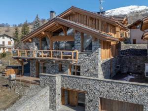 a house with a stone facade with a balcony at Chalet neuf avec piscine chauffée, espace détente, sauna, bain nordique et salle de cinéma - FR-1-570-57 in Saint-Marcel