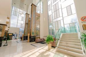 eine Lobby mit einer Treppe und großen Fenstern in der Unterkunft Adya Hotel Langkawi in Kuah