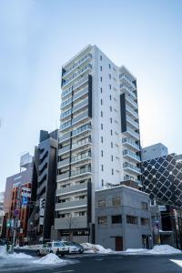a tall white building with cars parked in front of it at MOXIE in Sapporo