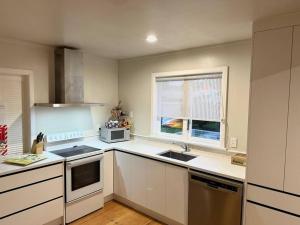 a kitchen with white cabinets and a sink and a window at Authentic Kiwi Lodge by the Lake in Rotorua