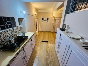 a kitchen with white cabinets and a wooden floor at Heritage Inn Homestay in Sibsāgar