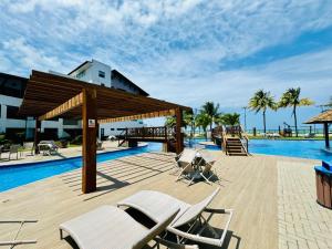 Una piscina tipo resort con sillas y un pabellón. en Flat no Maui - Beira-mar - Tamandaré - Carneiros, en Tamandaré
