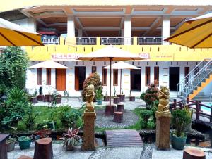a courtyard with tables and umbrellas in front of a building at Villa Cahaya 3 Guci Mitra RedDoorz in Tuwel