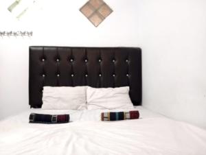 a bed with a black headboard and two pillows on it at Villa Cahaya 3 Guci Mitra RedDoorz in Tuwel