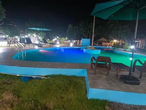 a swimming pool at night with chairs and an umbrella at Bamboo Garden Resort in Ban Phae Khwang