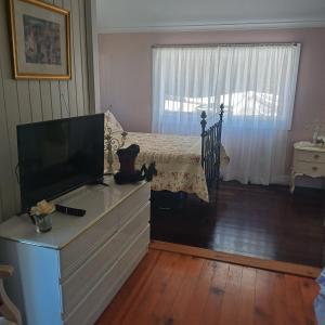 a bedroom with a dresser with a tv and a bed at Homestead BnB in Maudsland