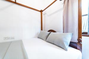 a bed with a pillow on it in a room with a window at Drifter - Rooms & Food in Midigama