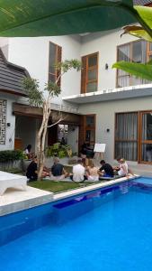 a group of people sitting around a swimming pool at Vasudha Hostel Canggu in Canggu