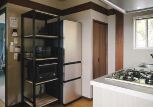 a kitchen with a white refrigerator and a stove at Tsugumori つぐもりステイ in Komoro