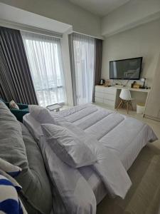 a large white bed with pillows in a bedroom at Green Sedayu Apartment Deluxe by Ellison in Jakarta
