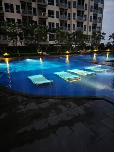 a swimming pool with mattresses in a building at night at Green Sedayu Apartment Deluxe by Ellison in Jakarta