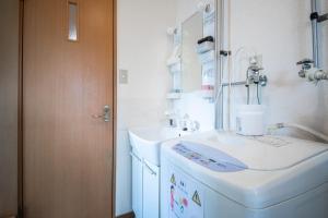 a bathroom with a sink and a washing machine at Sumiyoshi House Room A in Otaru