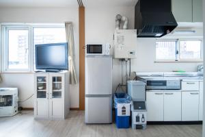 a kitchen with white appliances and a tv in it at Sumiyoshi House Room A in Otaru +22 photos