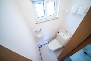 a white toilet in a bathroom with a window at Sumiyoshi House Room A in Otaru