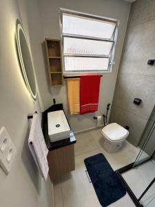 een badkamer met een wastafel en een toilet en een raam bij Apartamento Gonzaga Conforto in Santos