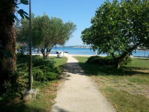 a walking path next to a beach with trees at Apartments Roncevic in Zadar