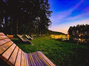 a row of benches sitting next to a lake at Ulęgałki Roztocze Stodoła in Jacnia