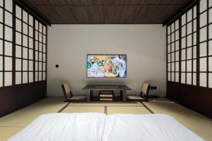 a room with a bed and a table with chairs at Addostays - Mori Machiya in Bandung