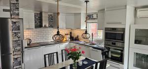 a kitchen with white cabinets and a table with flowers at Villa Relax in Mölnbo