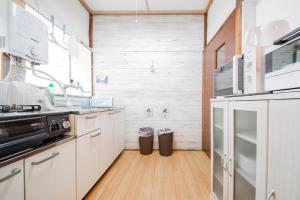 a kitchen with white cabinets and a wooden floor at TARUNE in Otaru