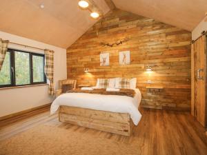 a bedroom with a bed in a room with wooden walls at Bwncath in Welshpool